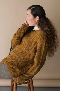 Oversized knitted sweater with cables in ochre yellow.