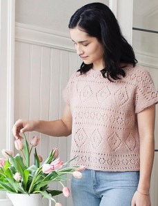 Model wearing oversized, pink, knitted top with pretty lace panels.