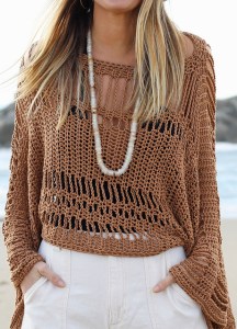 Model wearing oversized, knitted sweater with panels of wide, openwork mesh and lace, with flared sleeves.