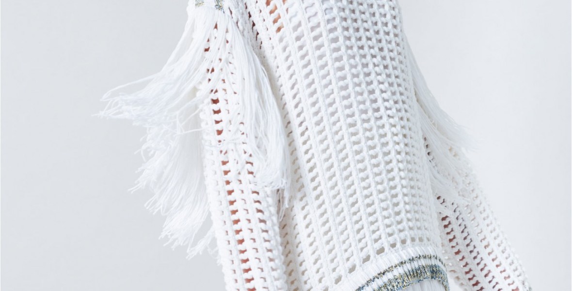 Model wearing Sonia Rykiel White knitted, oversized, white dress with allover mesh and fringe detail at back and hem.