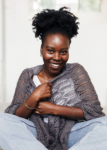 Woman wearing grey, linen, knitted shawl with all-over lace motifs.