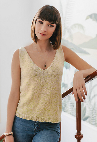 Woman wearing pale yellow, knitted tank top made out of cotton/linen blend, and with deep v-neck and rib detail at hem.