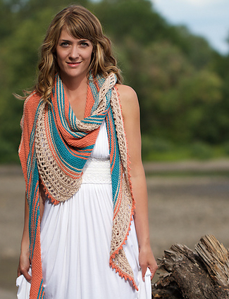 Woman wearing knitted, cotton/linen shawl in orange, blue and cream stripes of garter and lace.
