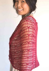 Woman wearing red, knitted linen cowl wrap with all-over dropped stitch cable design.